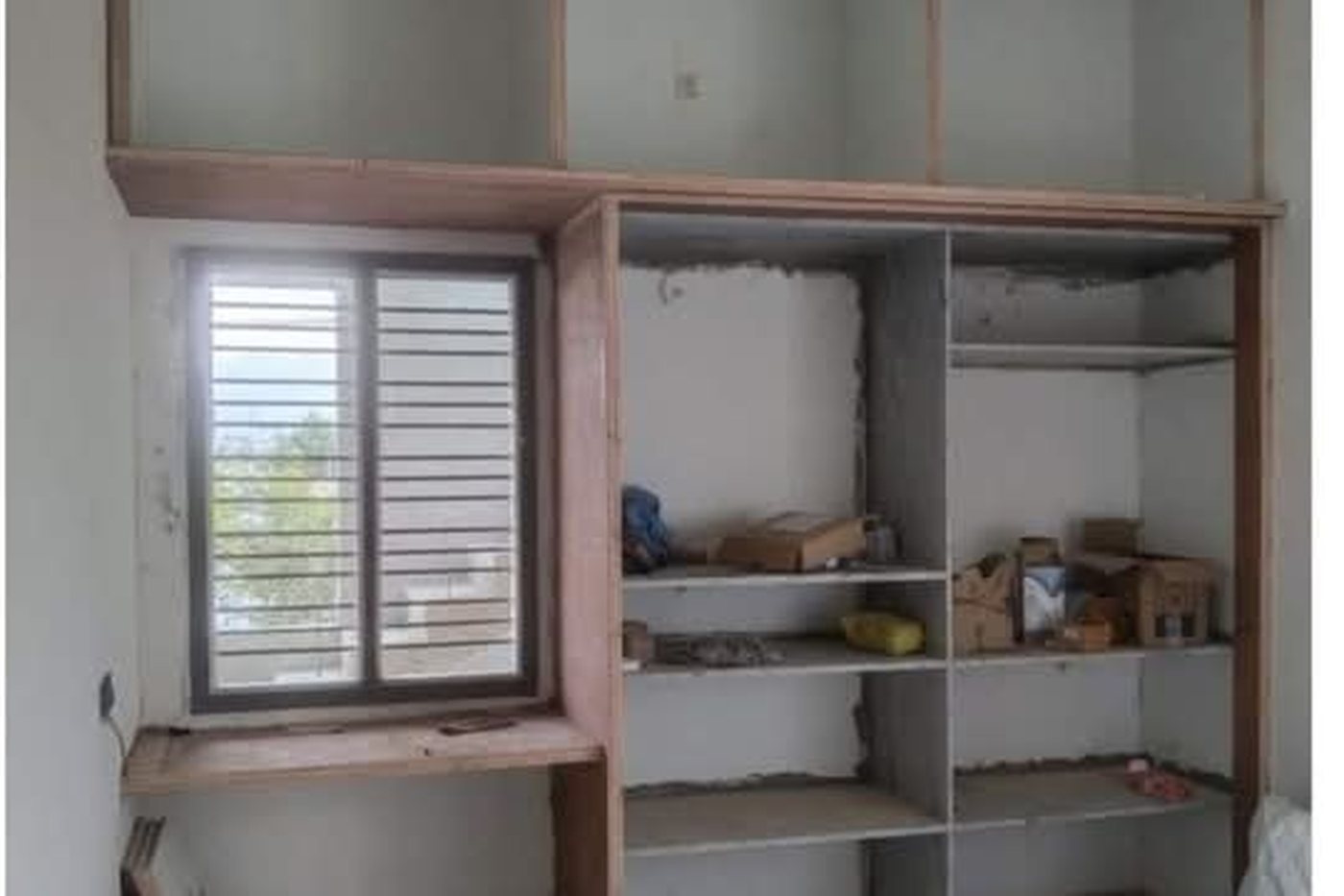 Before — the same wall as a bare plywood wardrobe carcass during fit-out