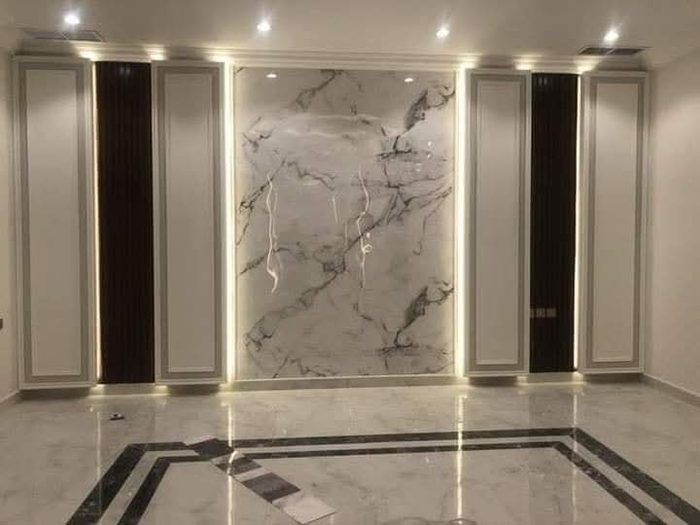 Marble-finish wall paneling with dark fluted panels and LED cove lighting